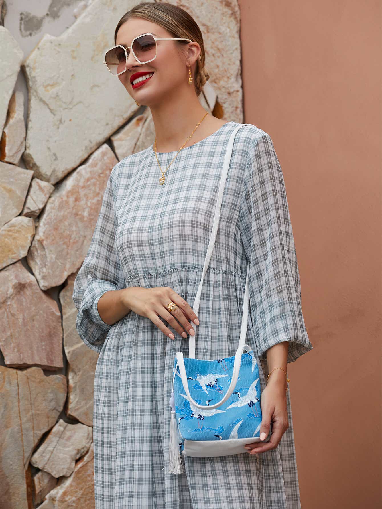 Model wearing blue canvas crossbody bag with hand-dyed crane design, blending traditional artistry with modern functionality.