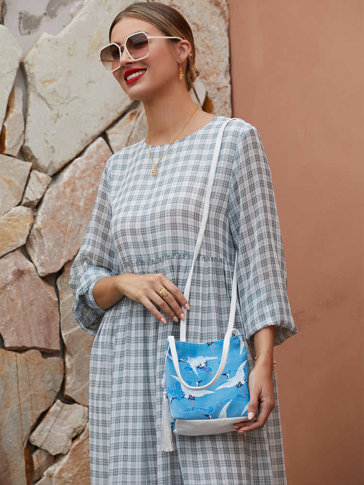 Model wearing blue canvas crossbody bag with hand-dyed crane design, blending traditional artistry with modern functionality.