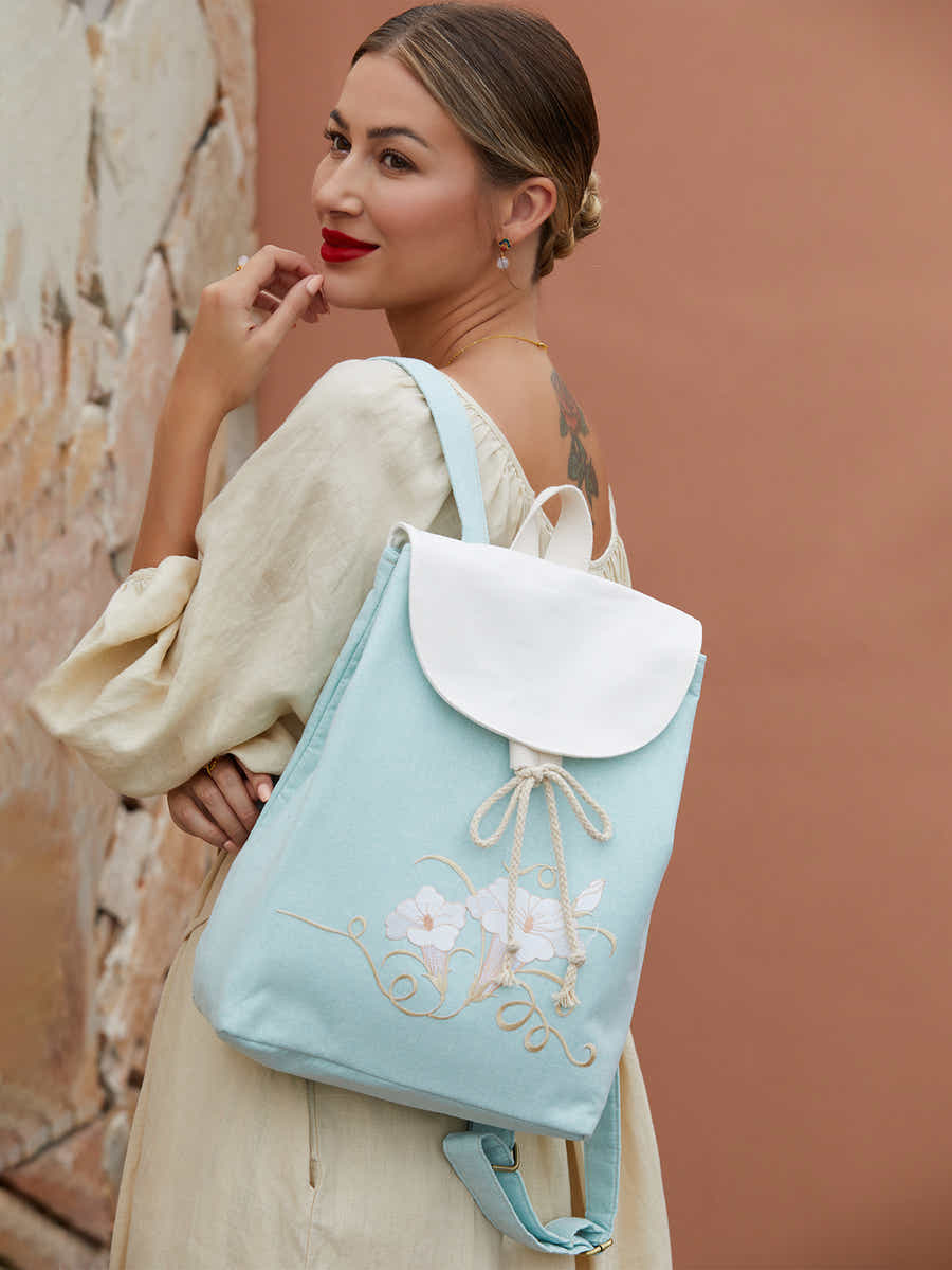 Side view of green canvas backpack featuring embroidered morning glory design, highlighting the sleek shape and quality craftsmanship.