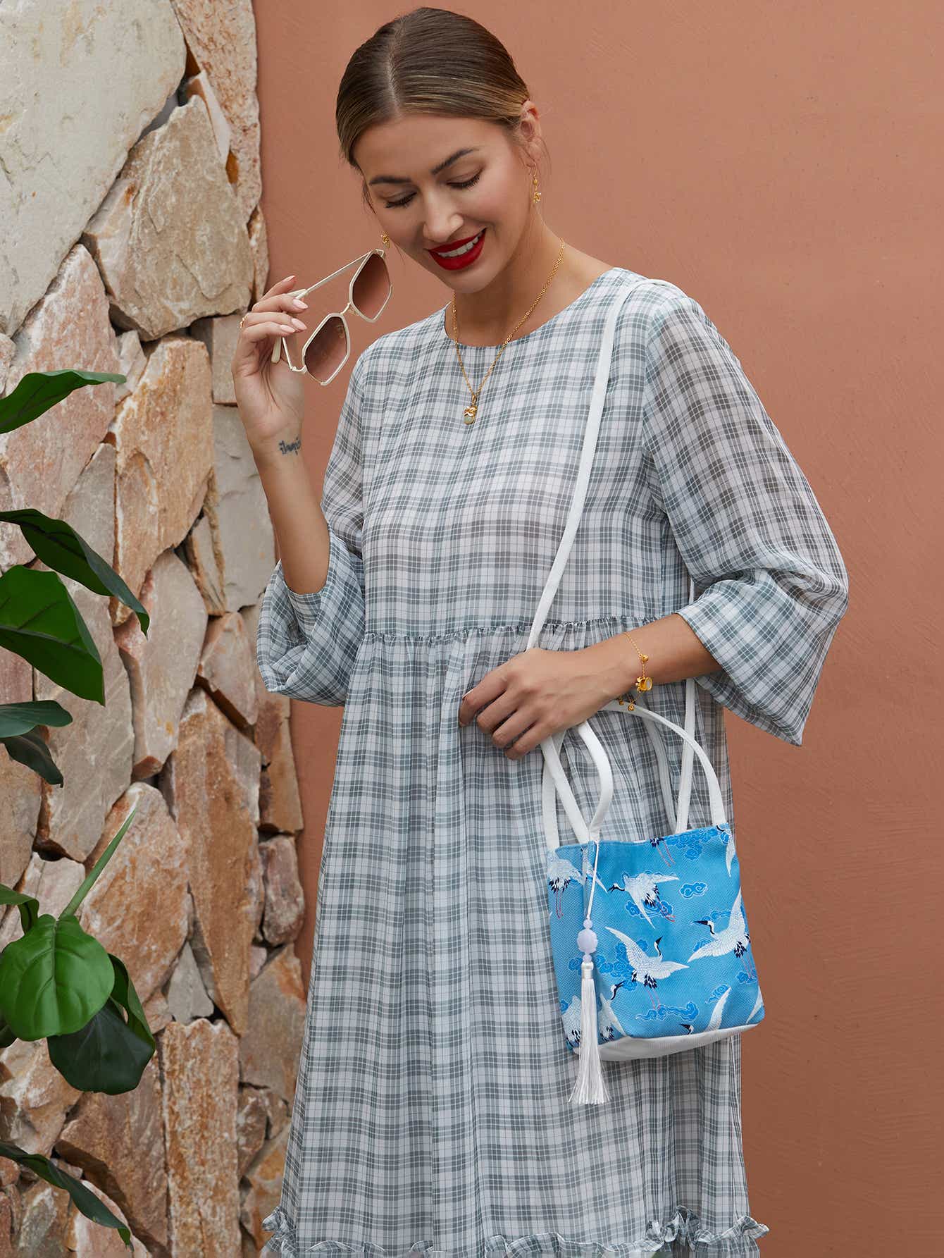 Model wearing blue canvas crossbody bag with hand-dyed crane design, blending traditional artistry with modern functionality.