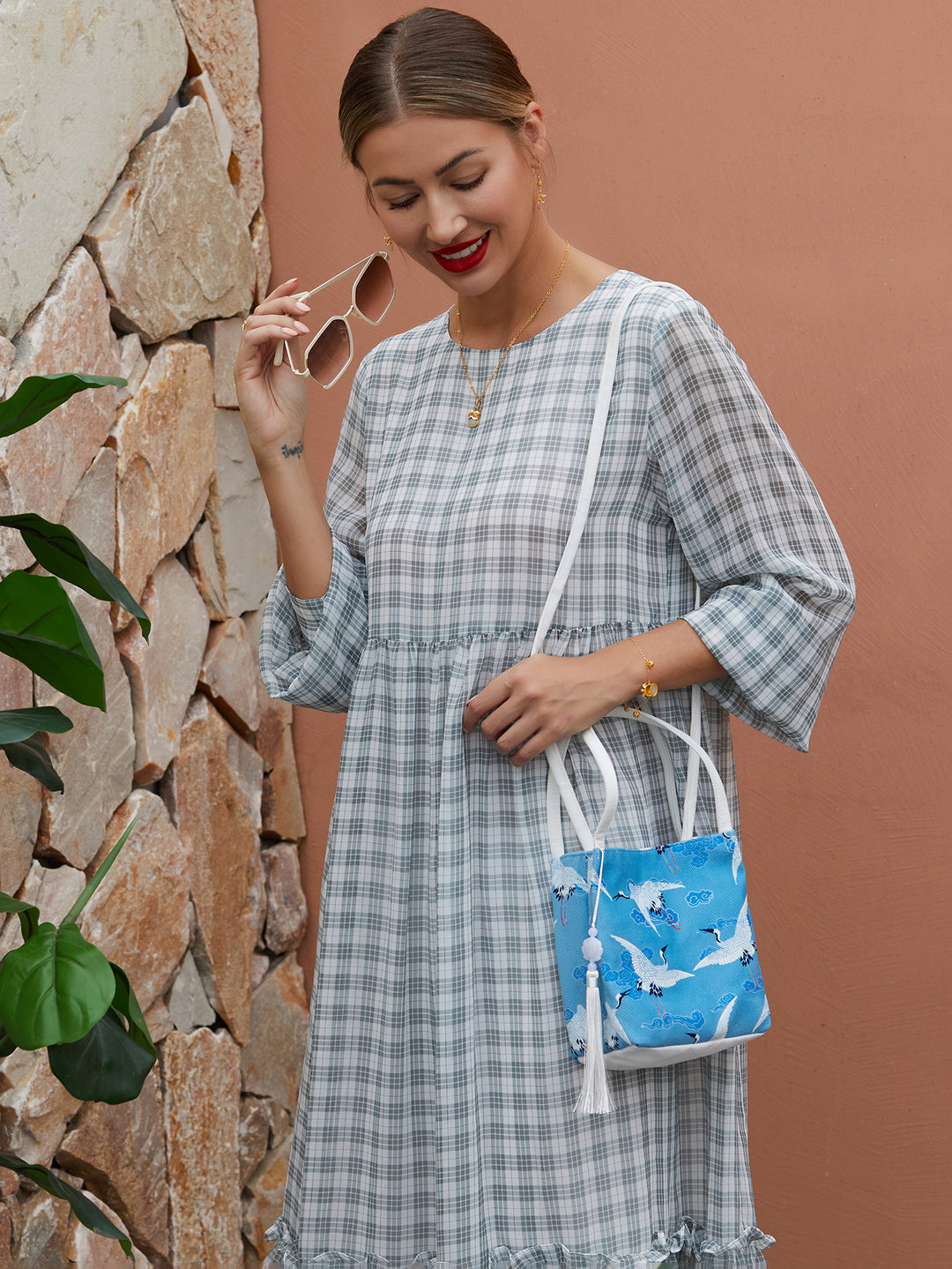 Model wearing blue canvas crossbody bag with hand-dyed crane design, blending traditional artistry with modern functionality.