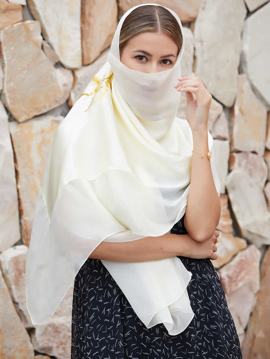 Close-up of delicate magnolia blossom embroidery on a pure white mulberry silk scarf, showcasing the artistry of Suzhou craftsmanship.