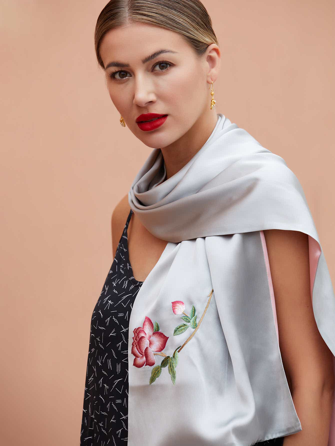Close-up of hand-stitched orange blossom embroidery on grey-pink mulberry silk scarf, highlighting the fine detail and elegance of Suzhou artistry.