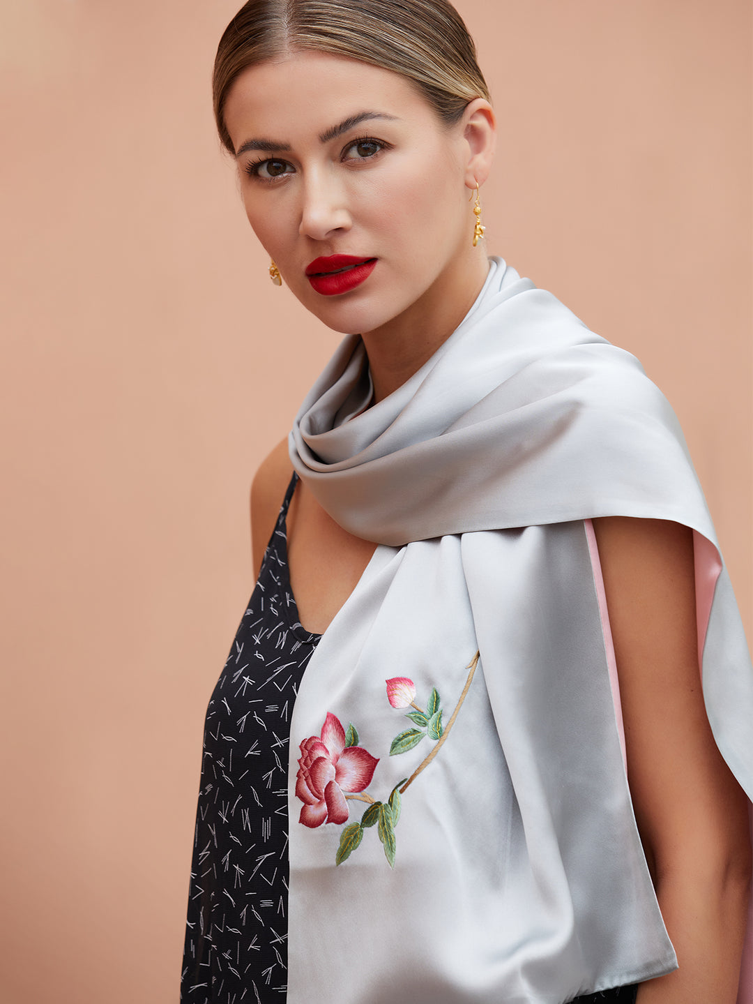 Close-up of hand-stitched orange blossom embroidery on grey-pink mulberry silk scarf, highlighting the fine detail and elegance of Suzhou artistry.