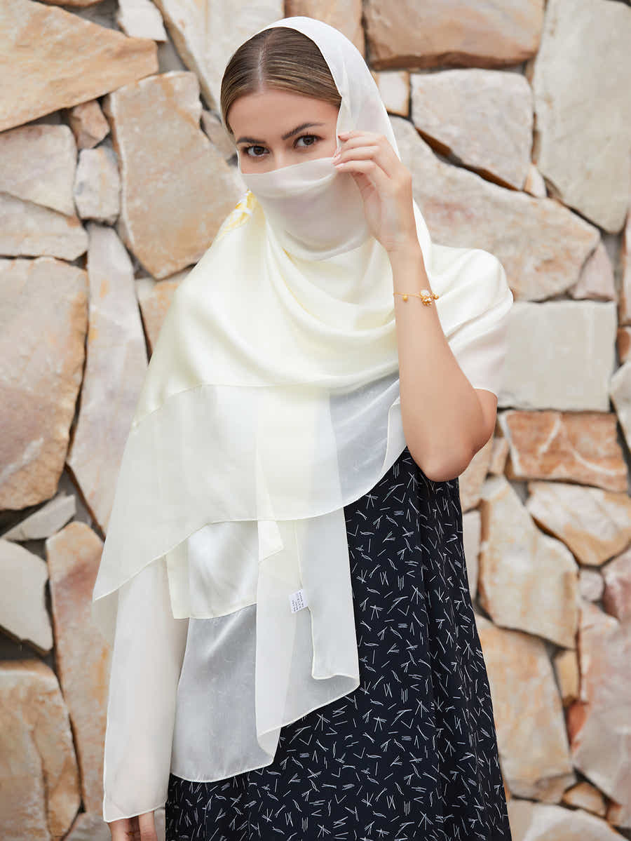 Detailed shot of the intricate hand-stitched magnolia blossoms on white mulberry silk scarf, reflecting Suzhou’s 2,500-year-old embroidery tradition.