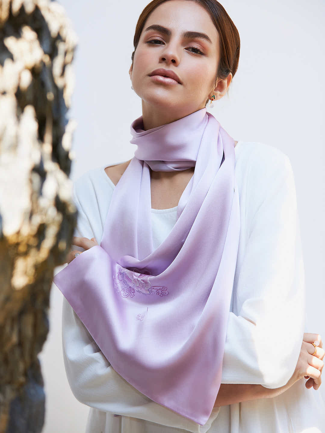 Pink peony embroidered silk scarf draped over a chair, demonstrating the fluidity and smoothness of premium mulberry silk.