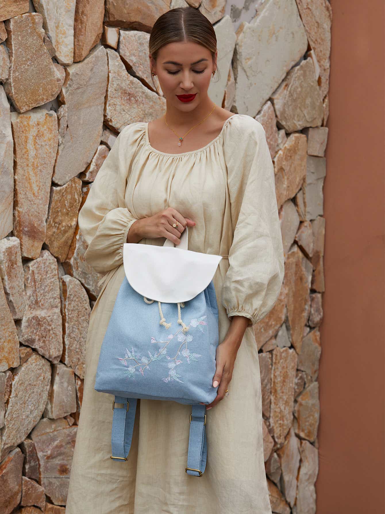 Interior view of blue canvas backpack with embroidered plum blossoms, showing spacious compartments and durable lining.