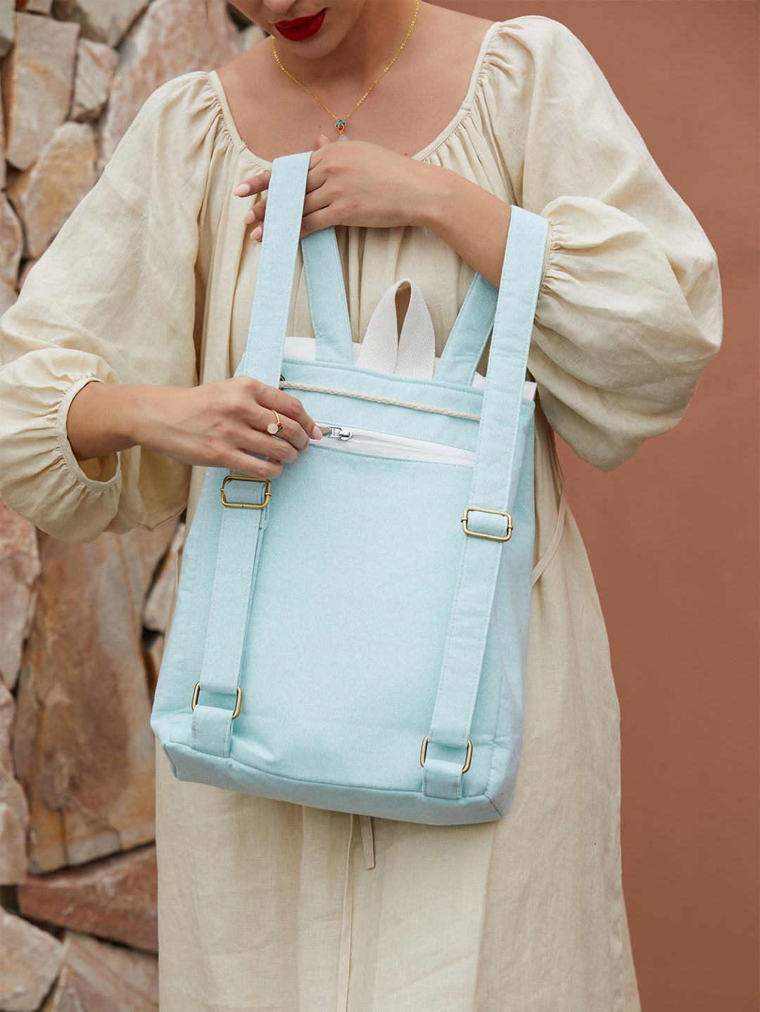 Detailed shot of green canvas backpack with embroidered morning glory flowers, featuring high-quality zippers and brand logo.
