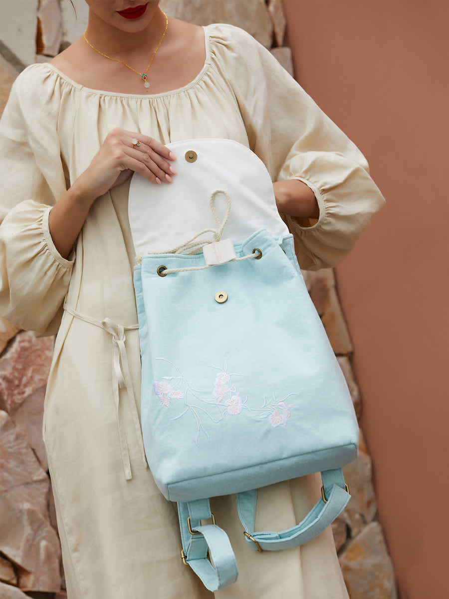Interior view of green canvas backpack with embroidered pear blossoms, showing spacious compartments and well-crafted lining.