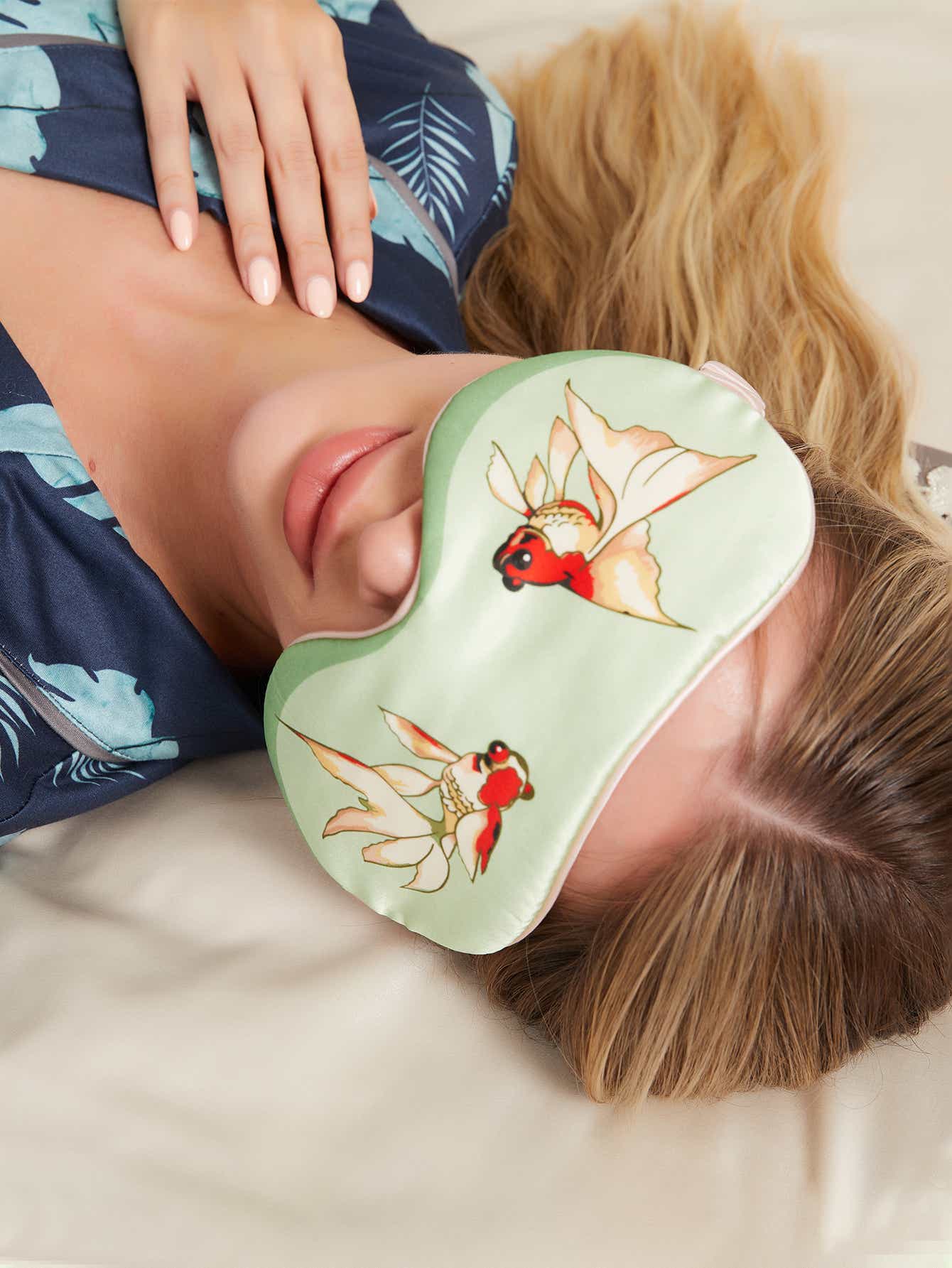 Model wearing green silk eye mask with goldfish design, showcasing its comfort and elegant Chinese-inspired design.