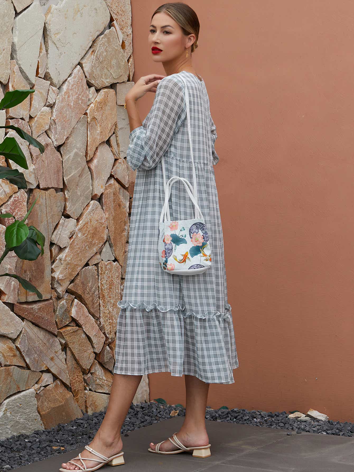 Model wearing white canvas crossbody bag with The Lotus Gatherers design, blending traditional artwork with contemporary functionality.