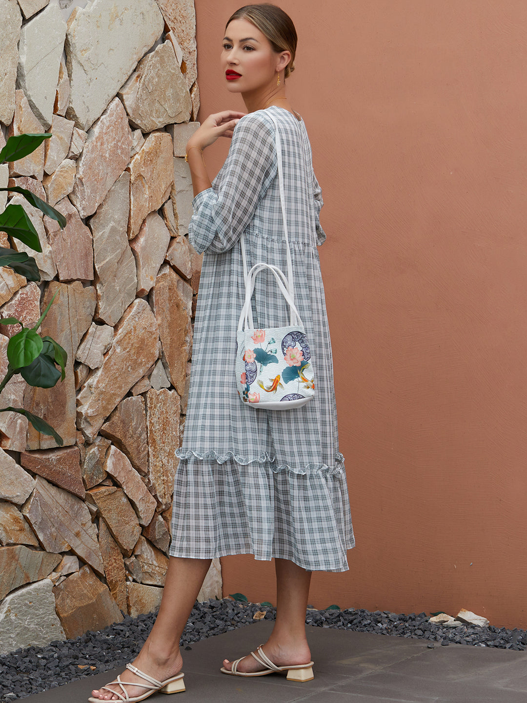 Model wearing white canvas crossbody bag with The Lotus Gatherers design, blending traditional artwork with contemporary functionality.