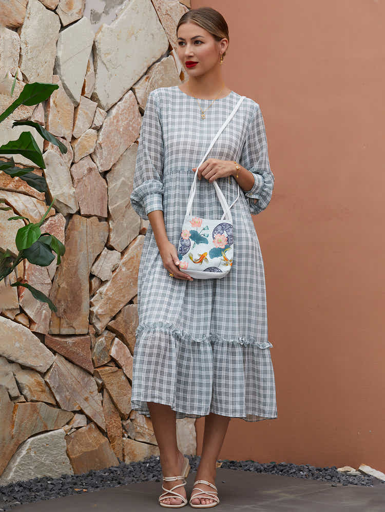 Side view of white canvas eco-friendly crossbody bag with The Lotus Gatherers design, showing sleek profile and adjustable strap.